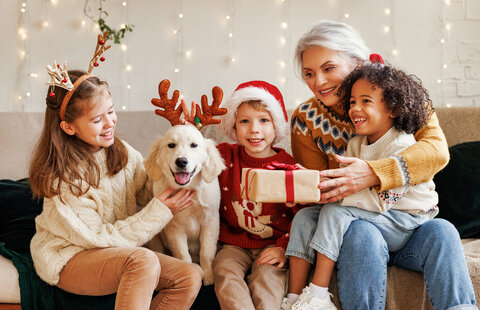 A woman with her grandchildren and dog at Christmas time.